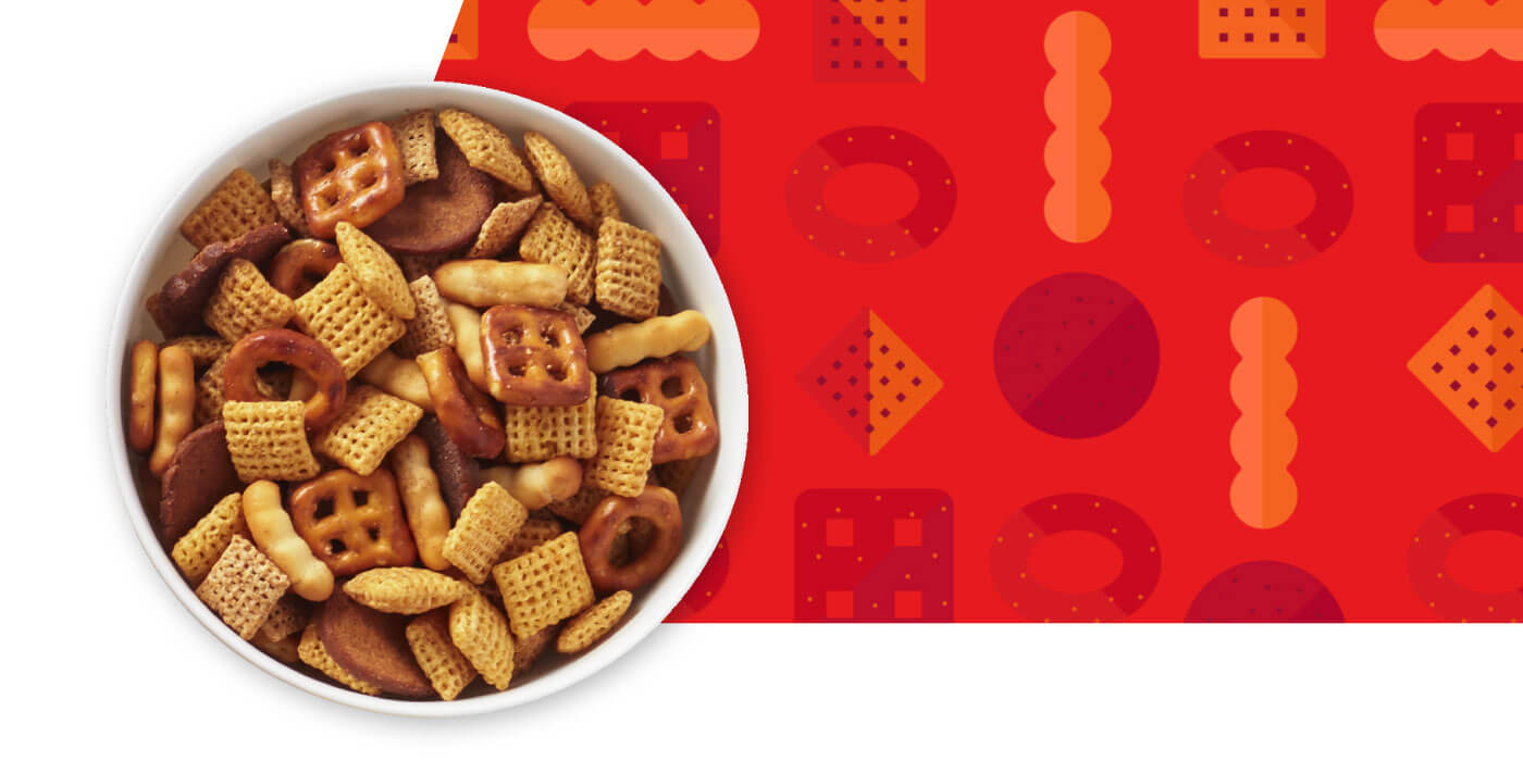 A white bowl filled with Chex Mix with red graphic with Chex Mix pieces pattern