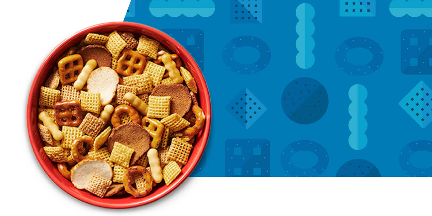 A red bowl filled with Chex Mix with blue graphic with Chex Mix pieces pattern